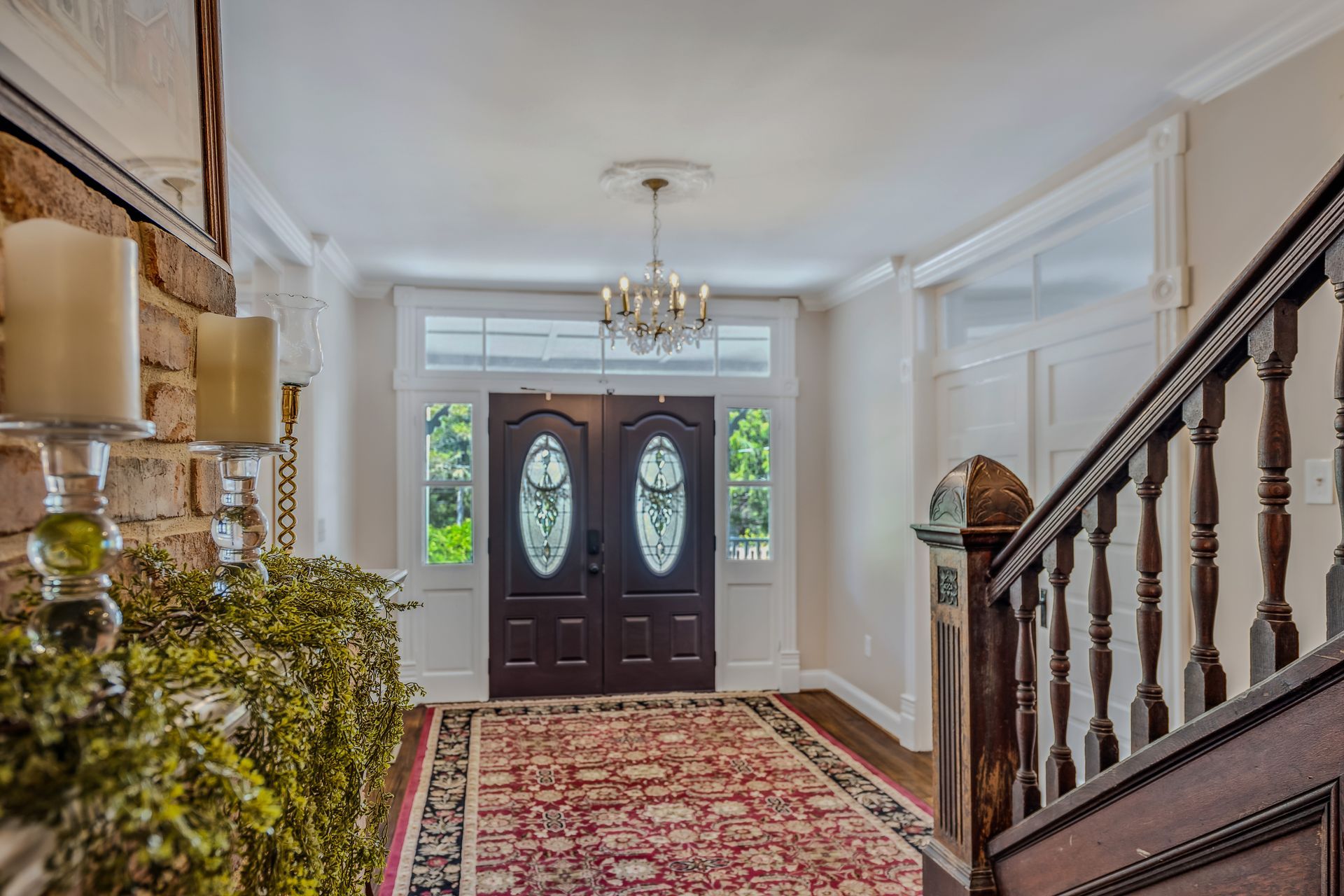 A hallway with a rug and stairs leading to a door.
