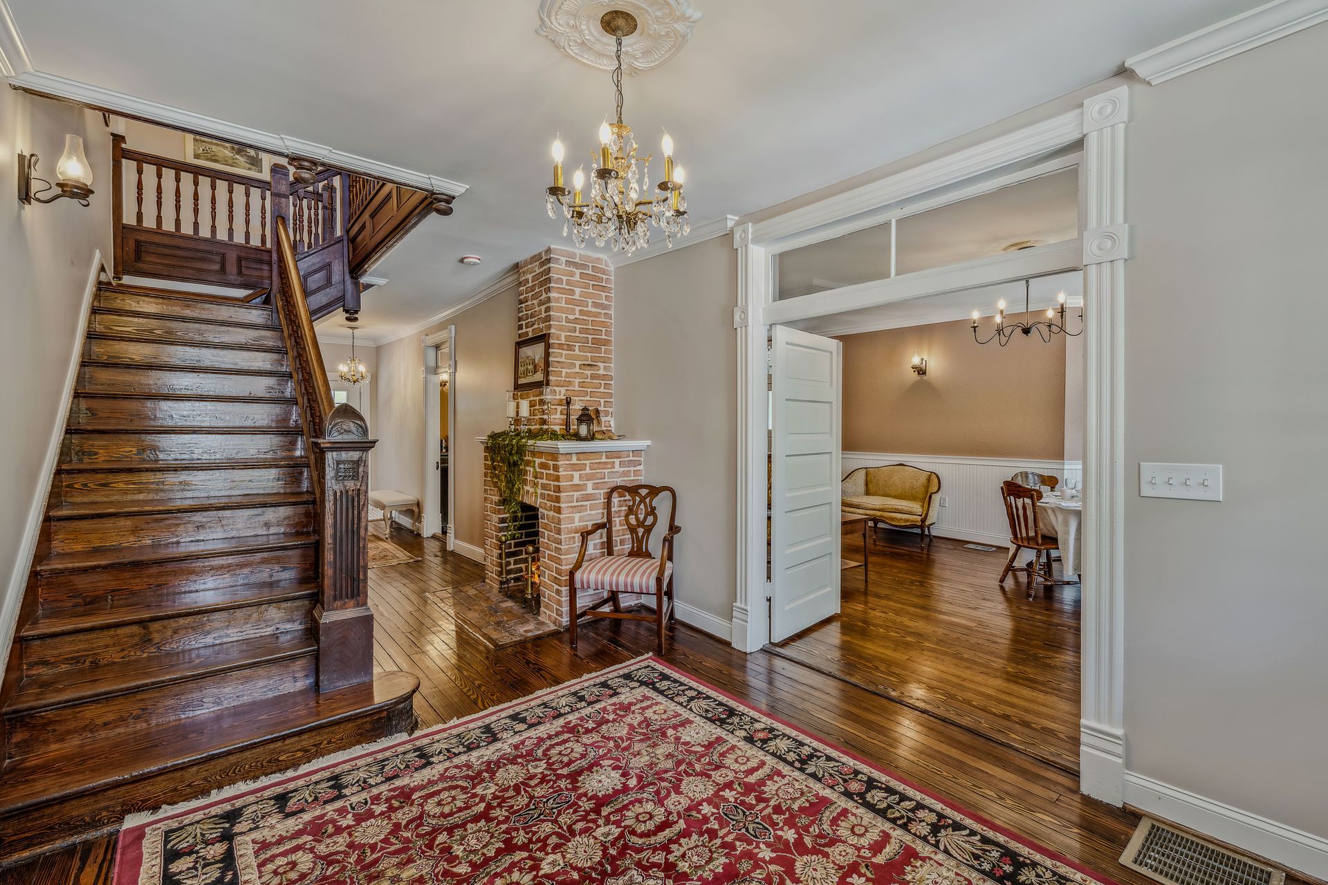 A hallway with stairs and a rug in a house.