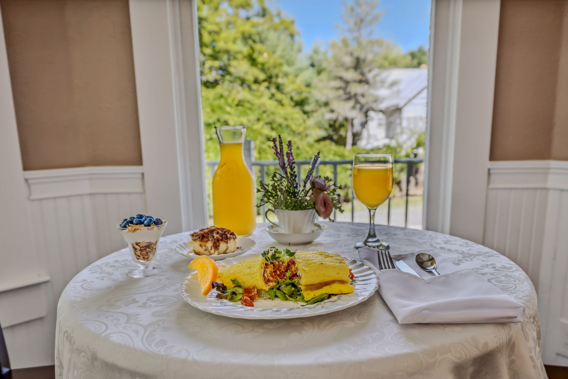 A table topped with a plate of food and a glass of orange juice.