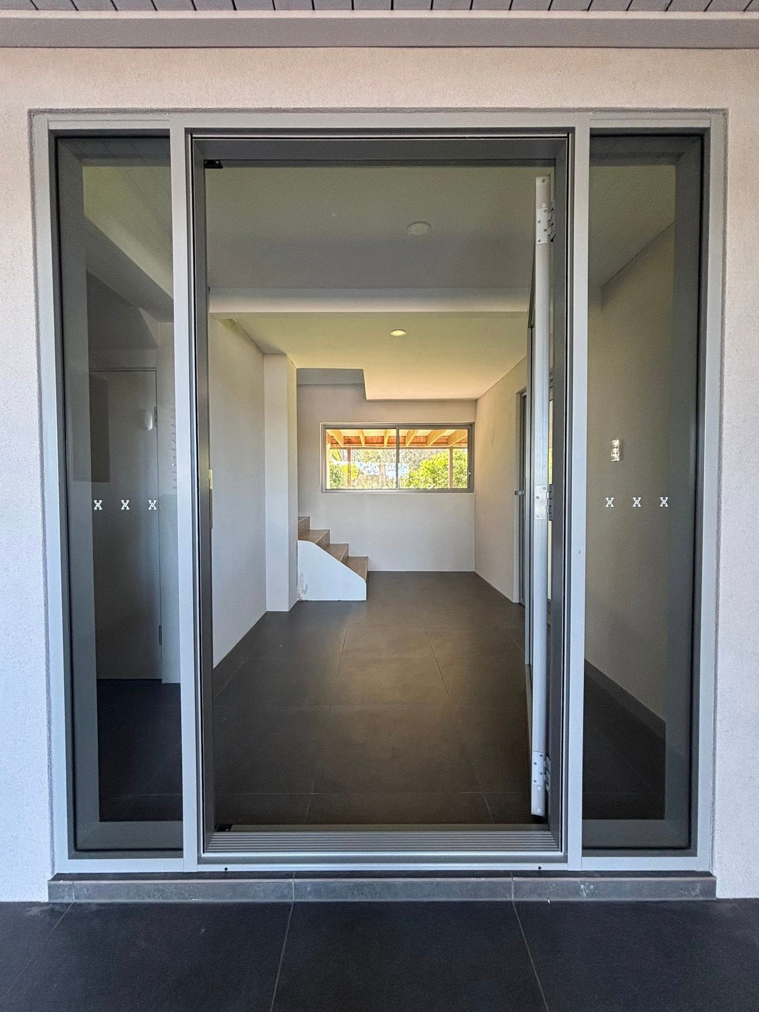 Glass Sliding Door Looking Into an Empty Room With Stairs and a Window — Brayden Stewart Building In Tuncurry, NSW