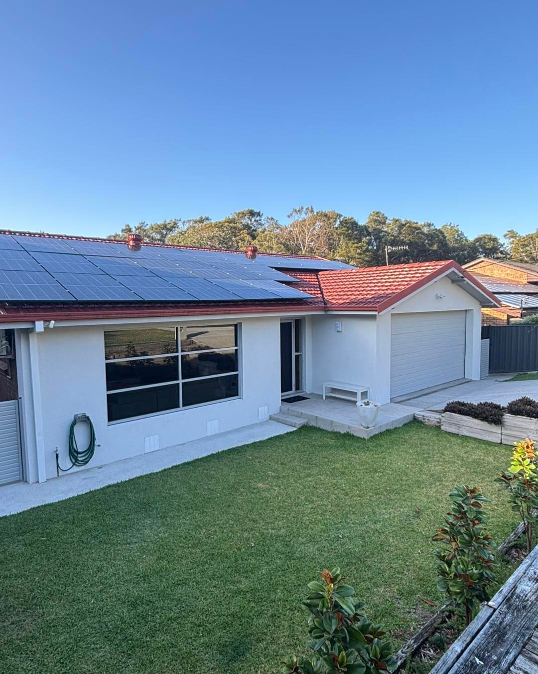 White House With Red Tile Roof, Solar Panels, and Green Lawn — Brayden Stewart Building In Forster, NSW