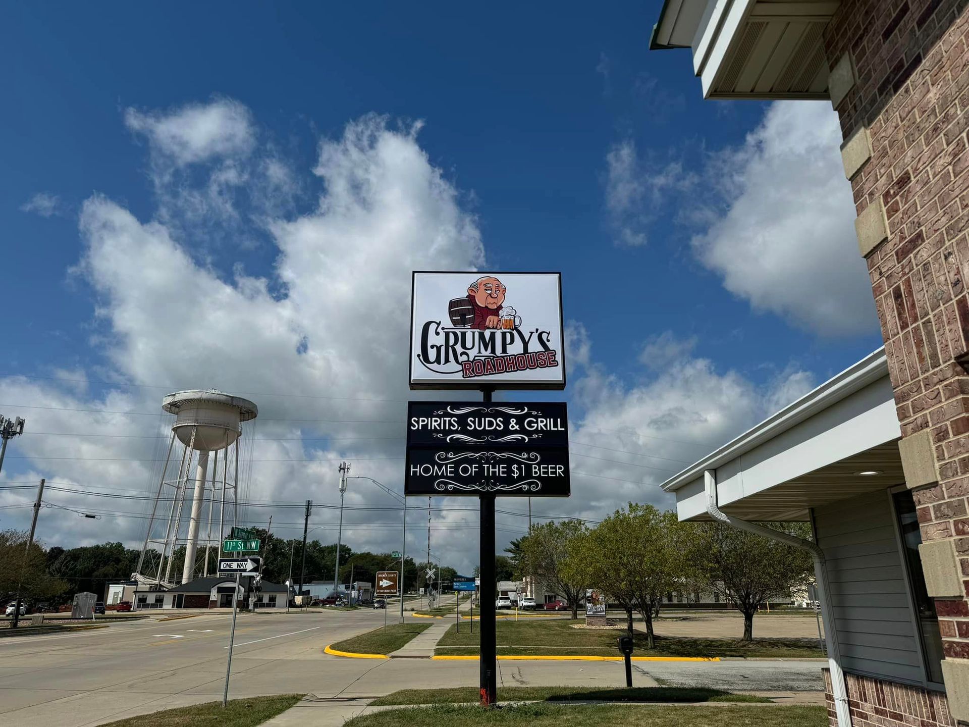 A sign for grumpy 's restaurant is on a pole in front of a brick building.