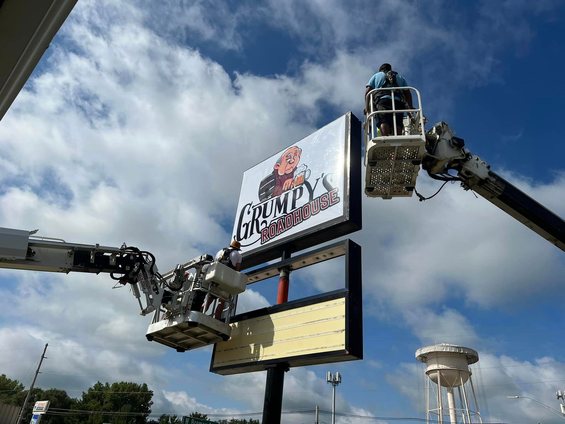 A man in a bucket is hanging a sign on a crane.