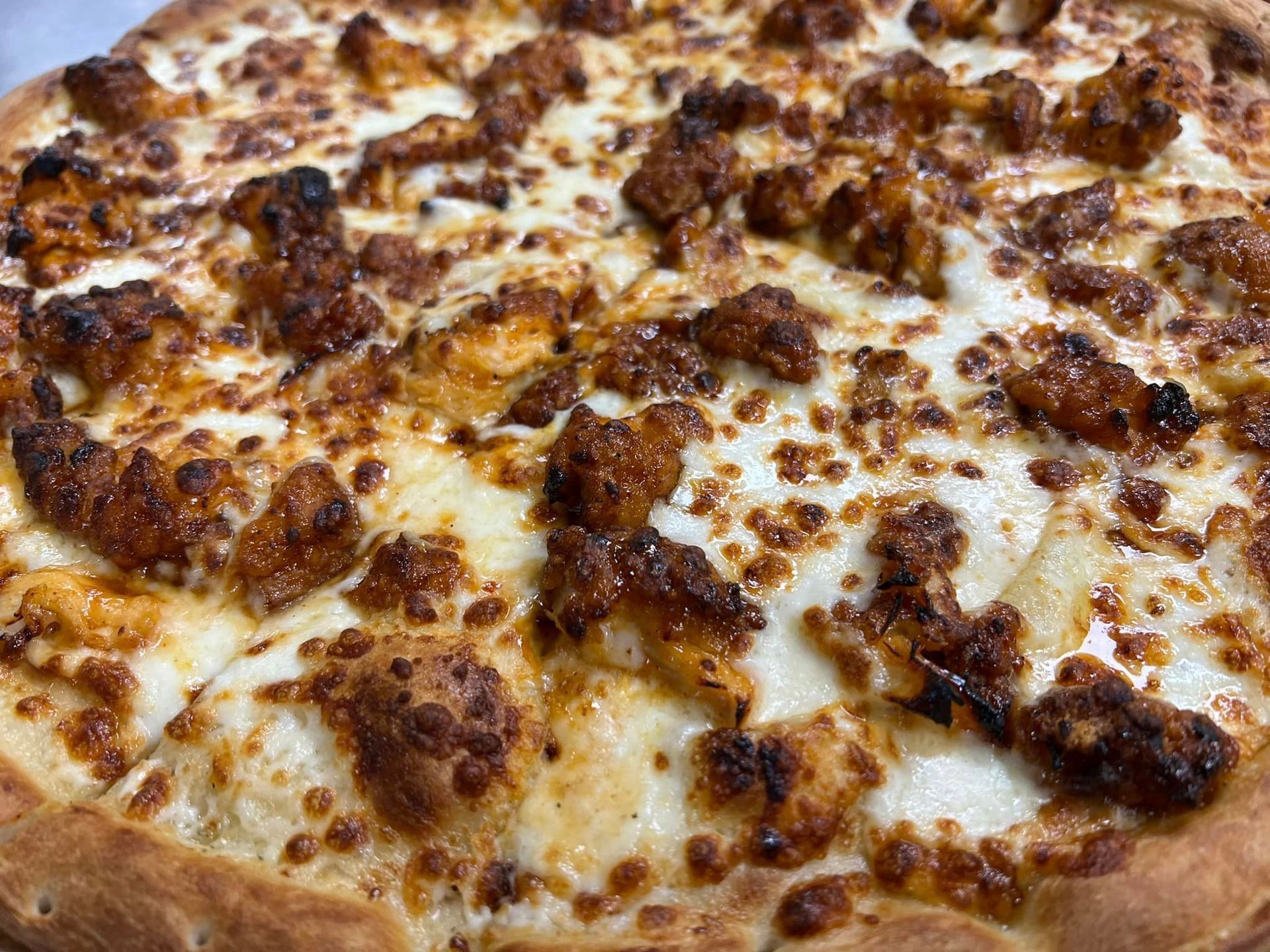 A close up of a pizza with chicken and cheese on a table.