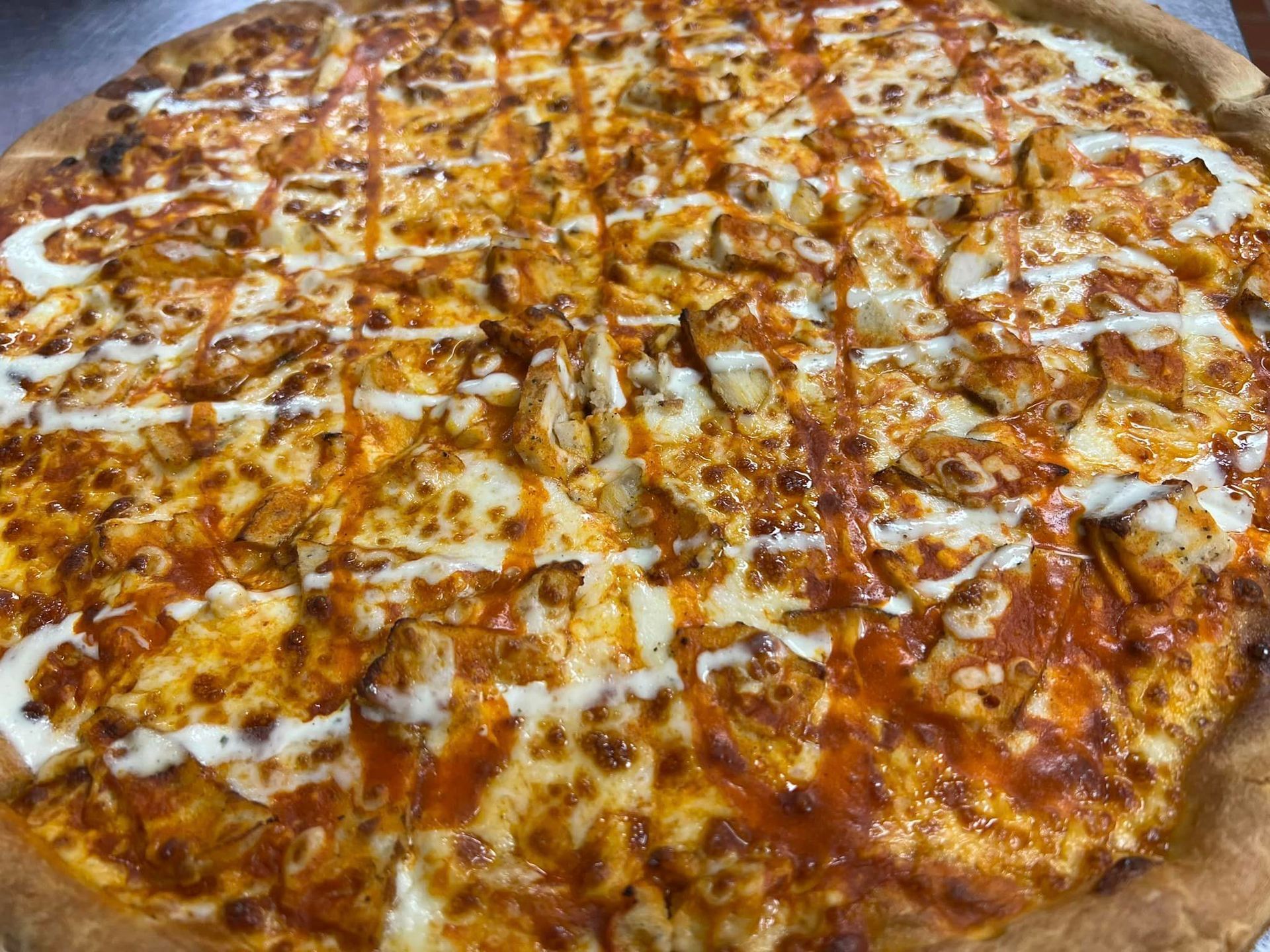 A pizza with chicken and cheese on it is sitting on a table.