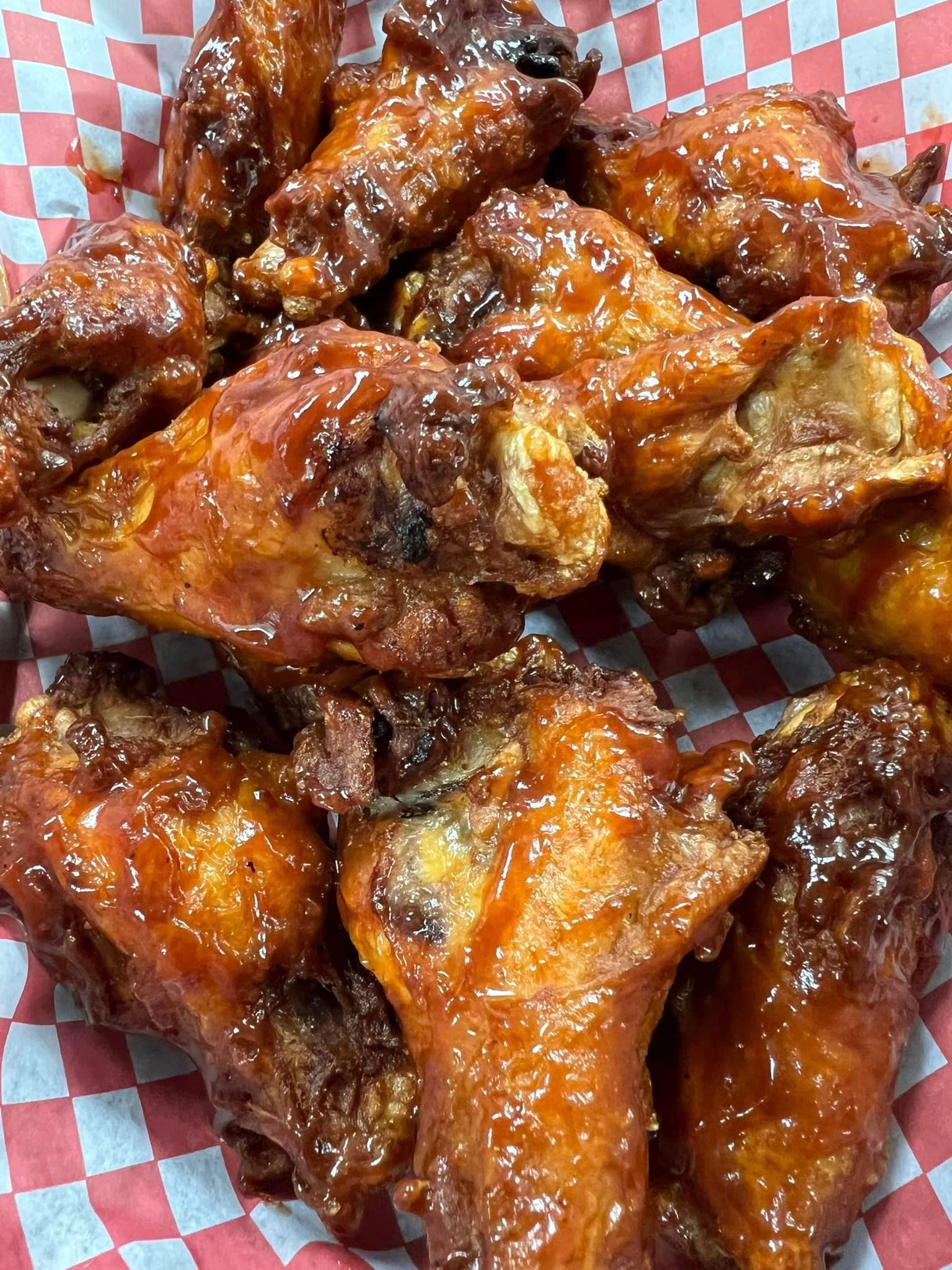 A close up of a basket of chicken wings on a checkered paper.