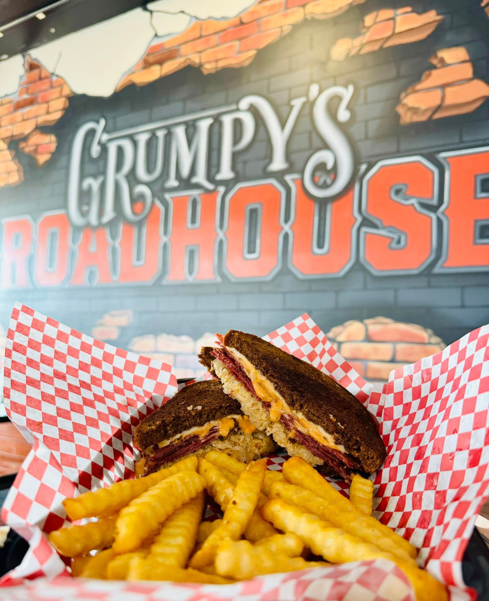A grumpy 's roadhouse sandwich and french fries in a basket