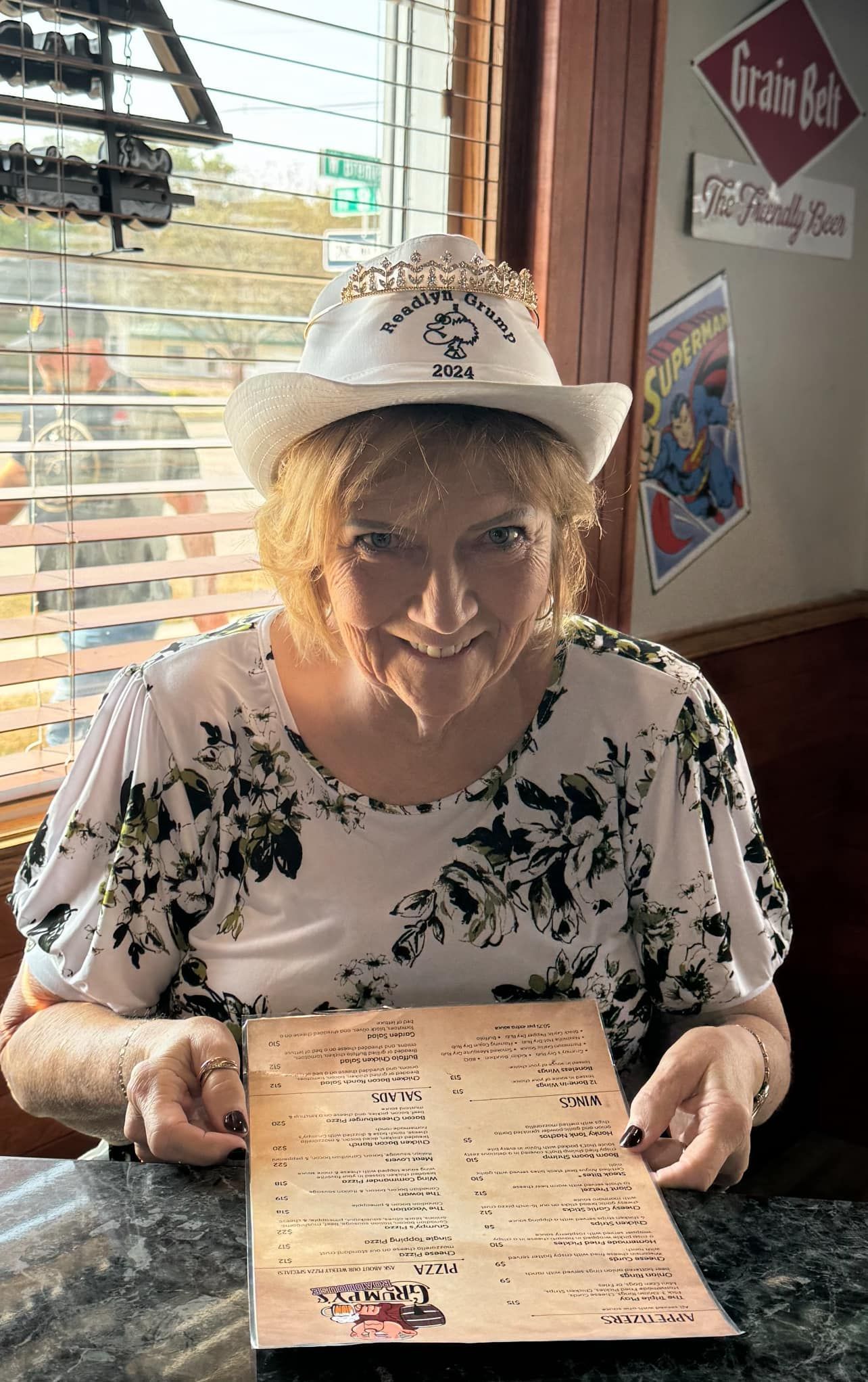 A woman wearing a cowboy hat is sitting at a table holding a menu.