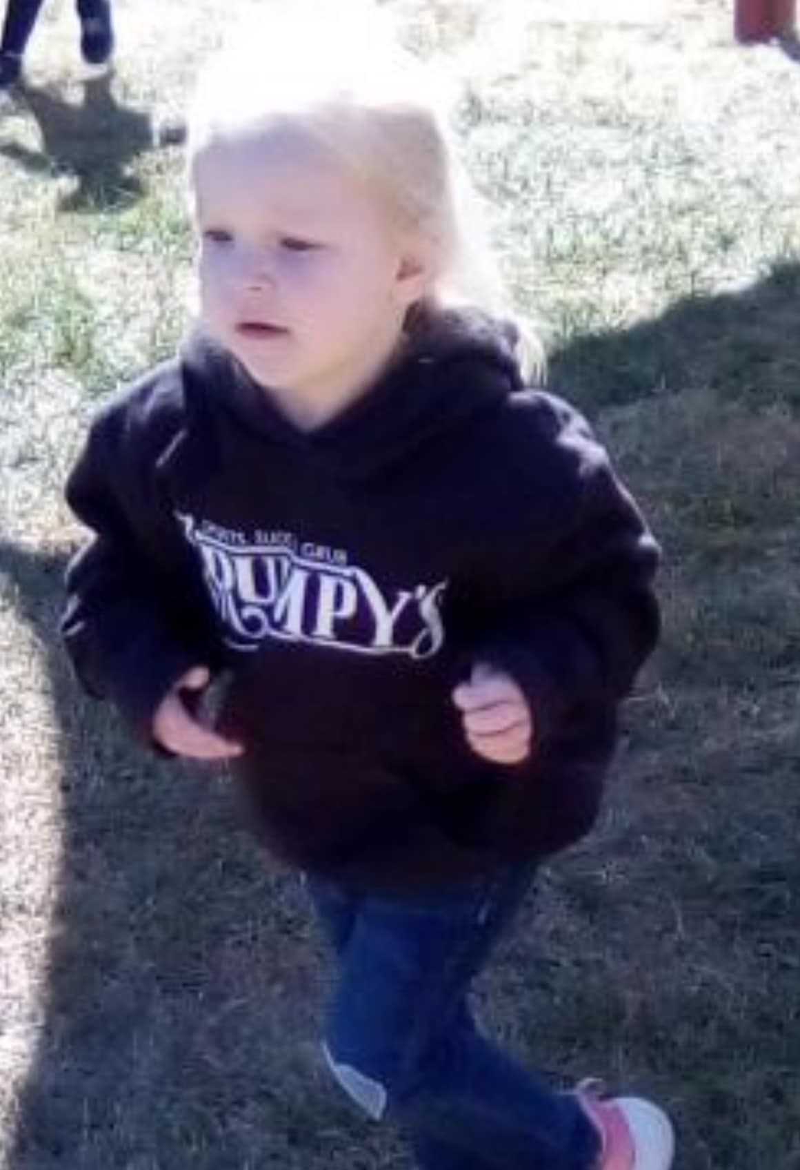 A little girl wearing a black hoodie that says pumpy 's
