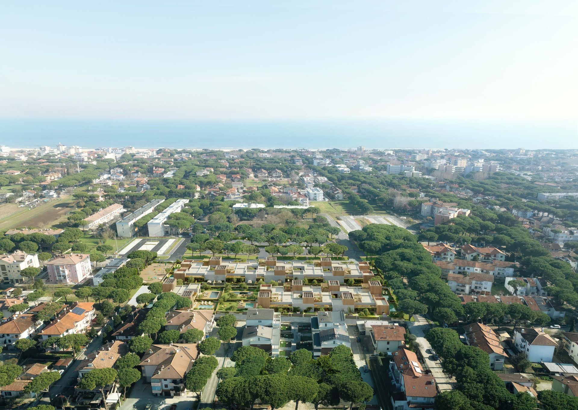 Vista aerea di una città costiera con edifici, alberi e una lunga strada.