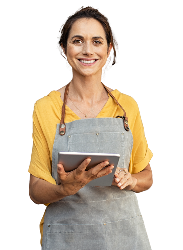 A woman in an apron is holding a tablet and smiling.