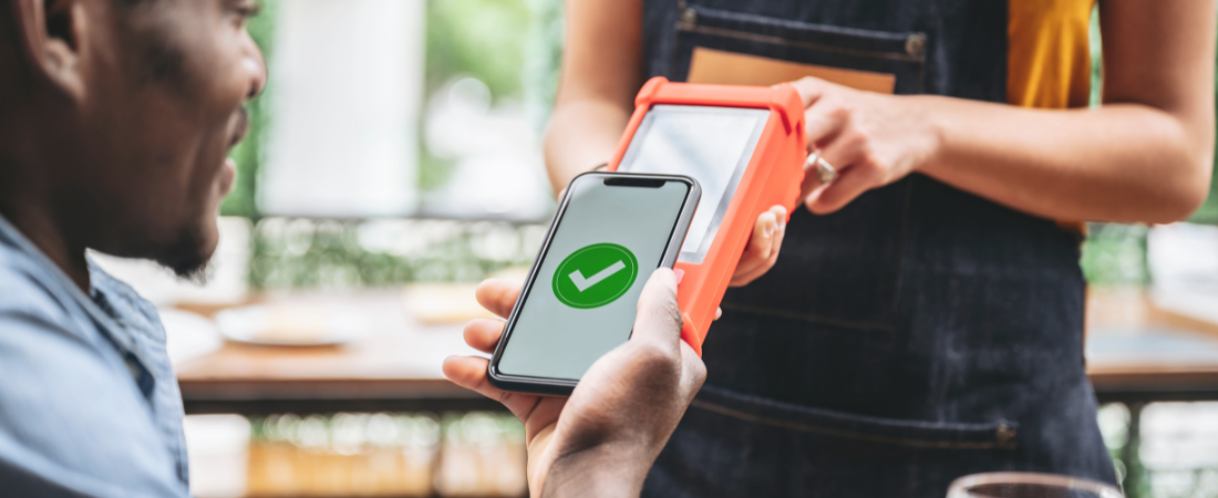 A man is paying with a cell phone in a restaurant.