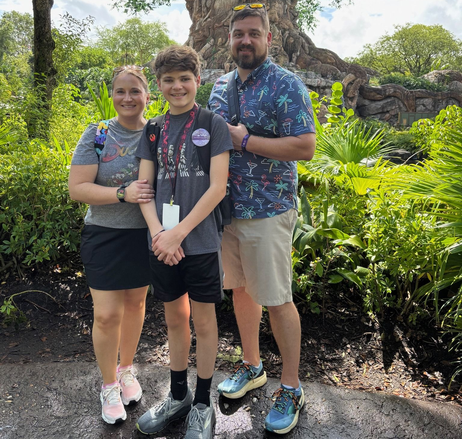 A smiling family stands together in front of the Tree of Life at Disney's Animal Kingdom park.