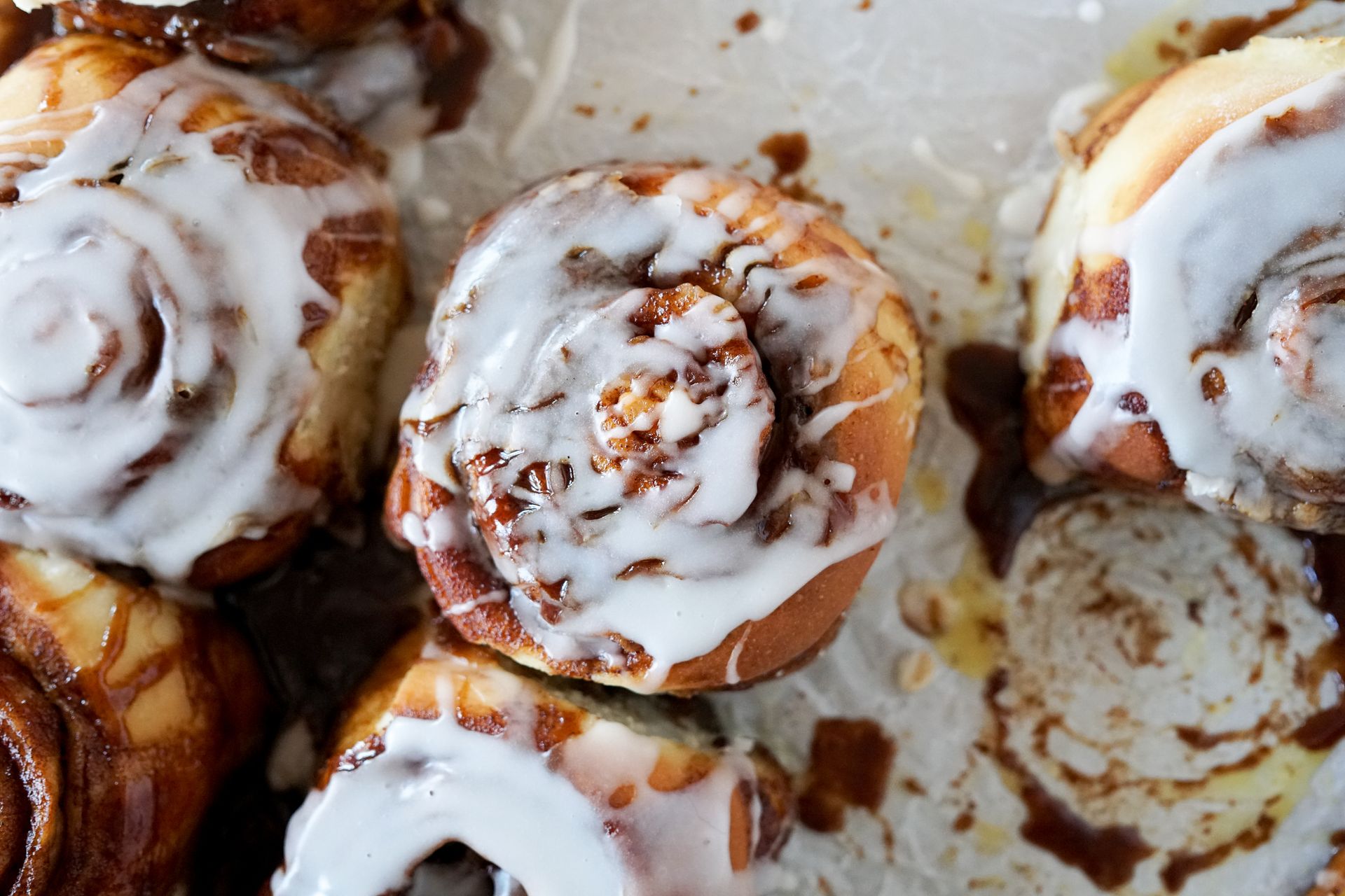 A bunch of cinnamon rolls with icing on them are sitting on a table.