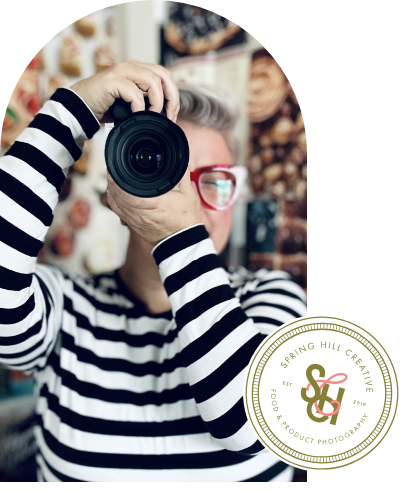 A man in a striped shirt is taking a picture with a camera.