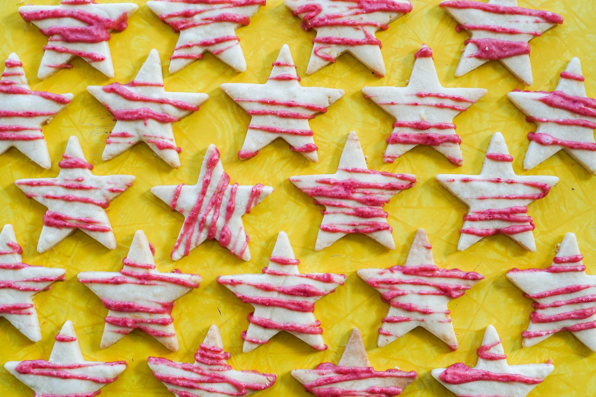 A bunch of cookies in the shape of stars on a yellow surface.