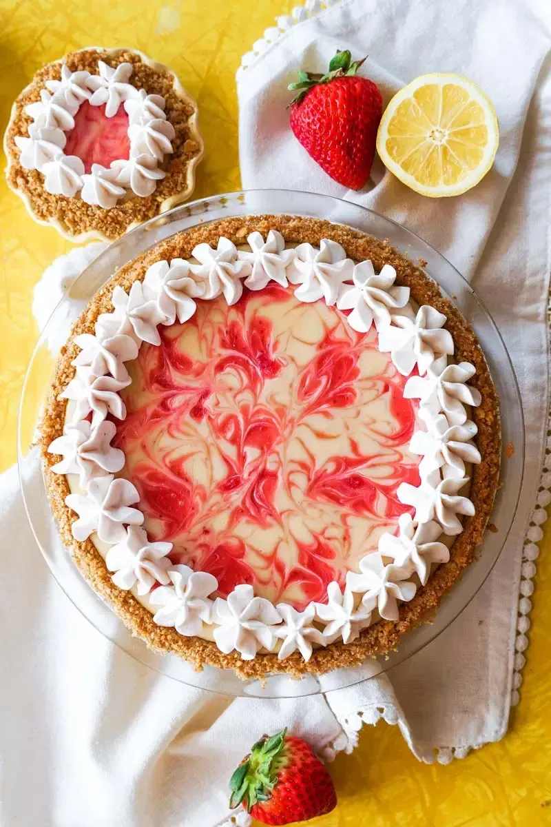 A strawberry lemon pie with whipped cream and strawberries on a table.