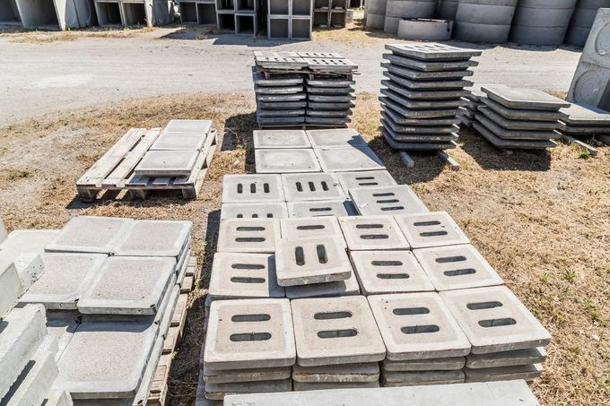Pile di lastre e blocchi di cemento in un cantiere edile all'aperto.