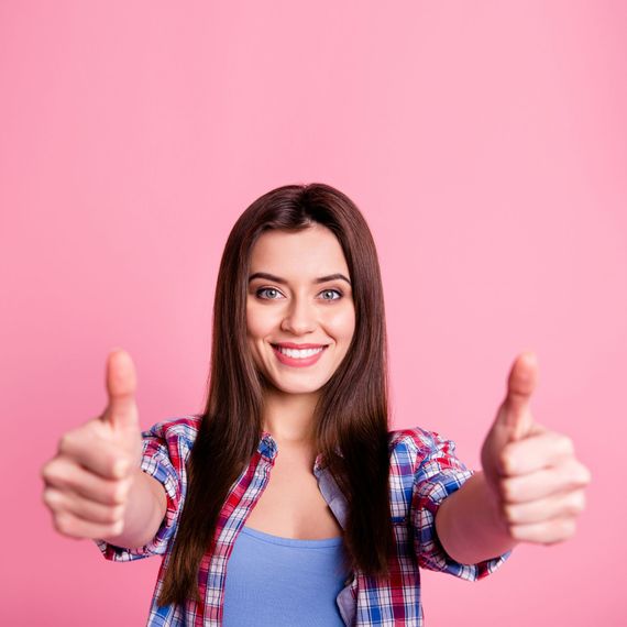 A woman is giving a thumbs up sign on a pink background.