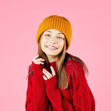 The girl is wearing a red sweater and a yellow hat.