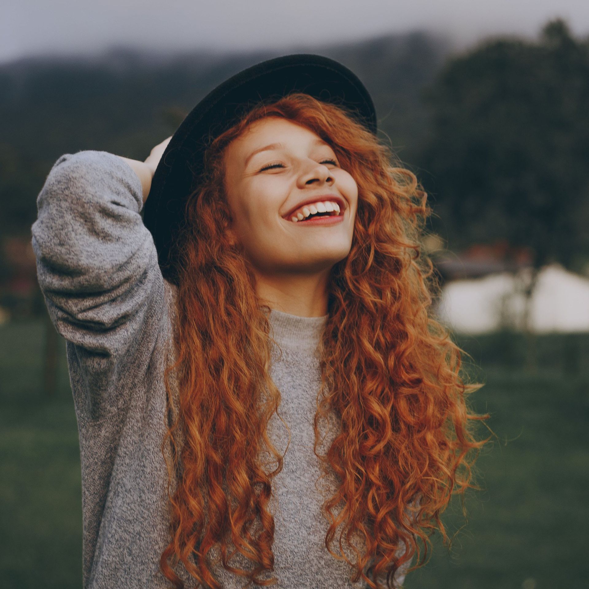 Redheaded woman with hat, smiling outside
