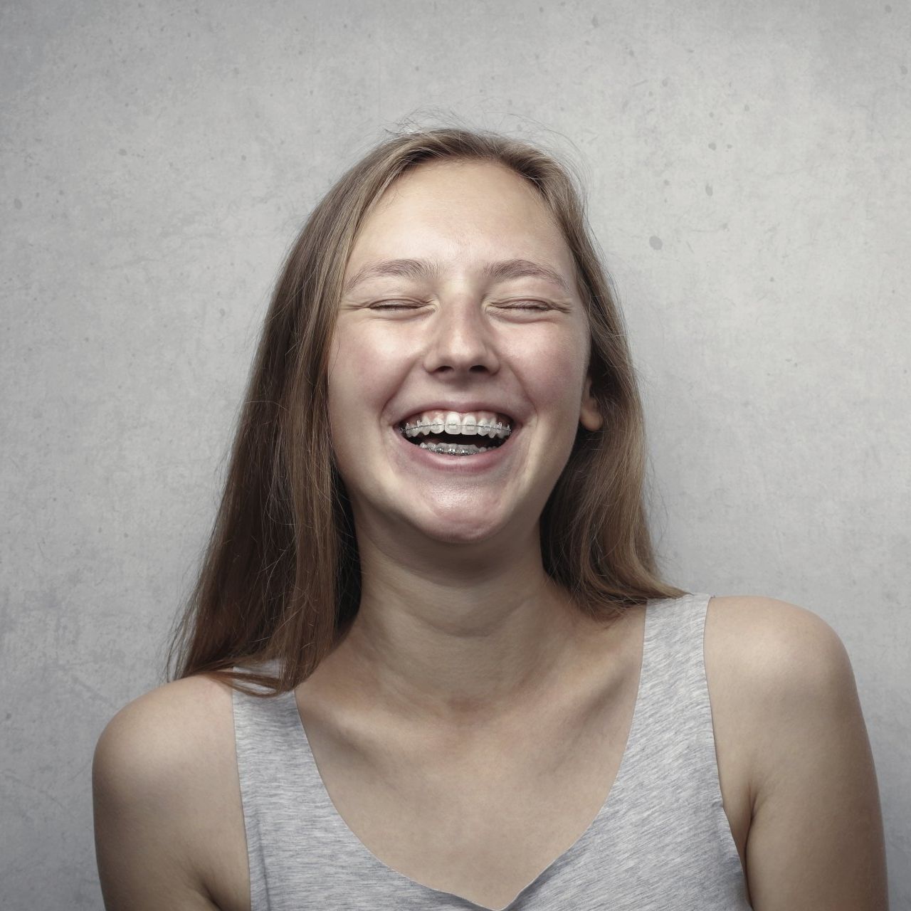 Teenage girl with braces, eyes closed, laughing