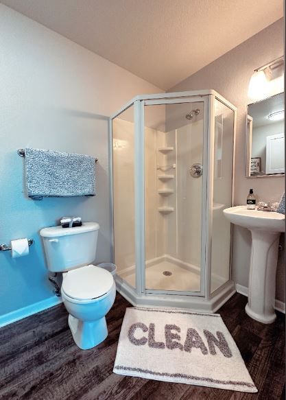 Bathroom with a white hexagonal shower, toilet, and sink. 