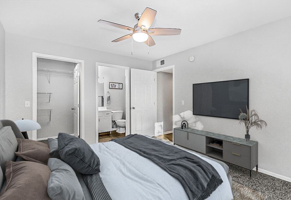 Bedroom with bed, TV, closet, bathroom, neutral colors, modern decor.