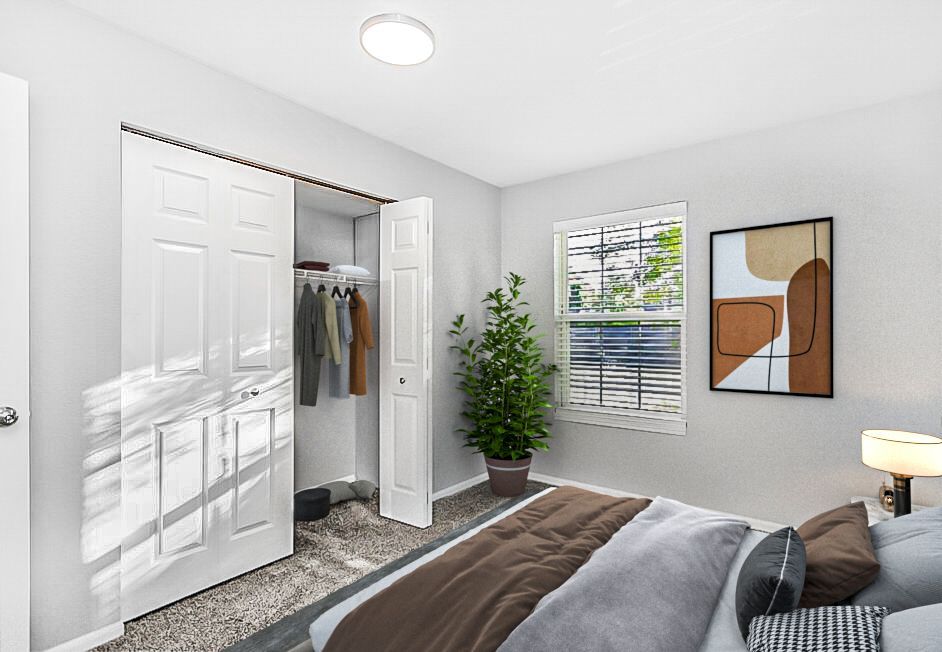 Bedroom with white walls, closet, bed, artwork, and window with blinds.