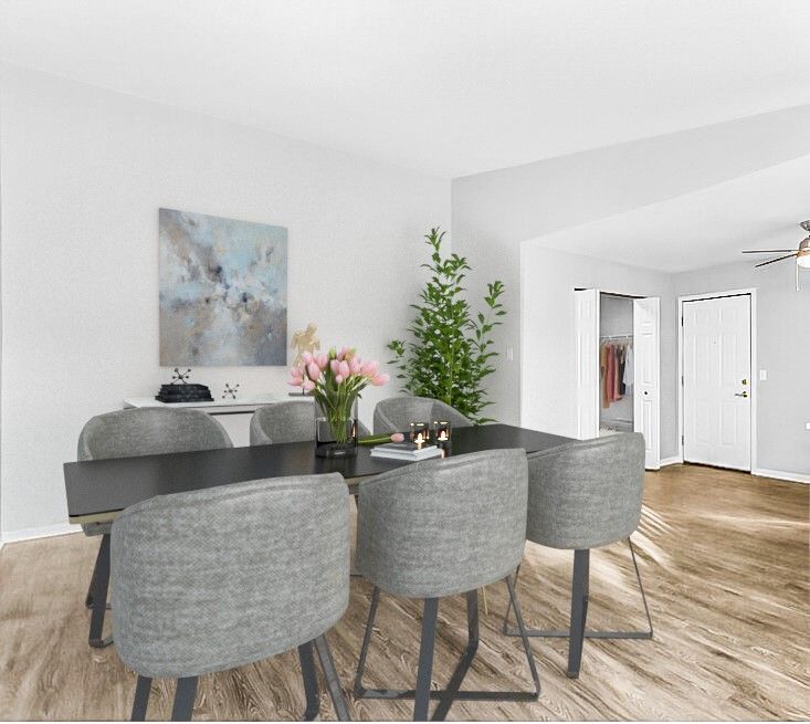 Dining room with dark table, gray chairs, artwork, and a plant.