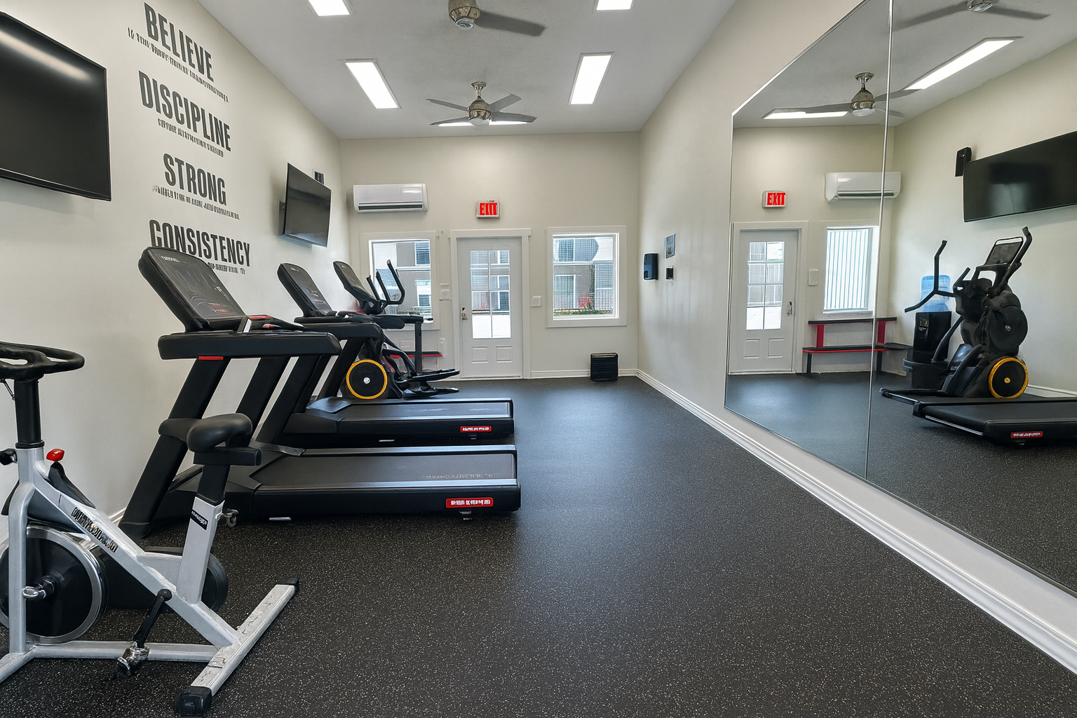 Gym with treadmills, stationary bike, elliptical, and large mirror. Black flooring, white walls, and TVs.