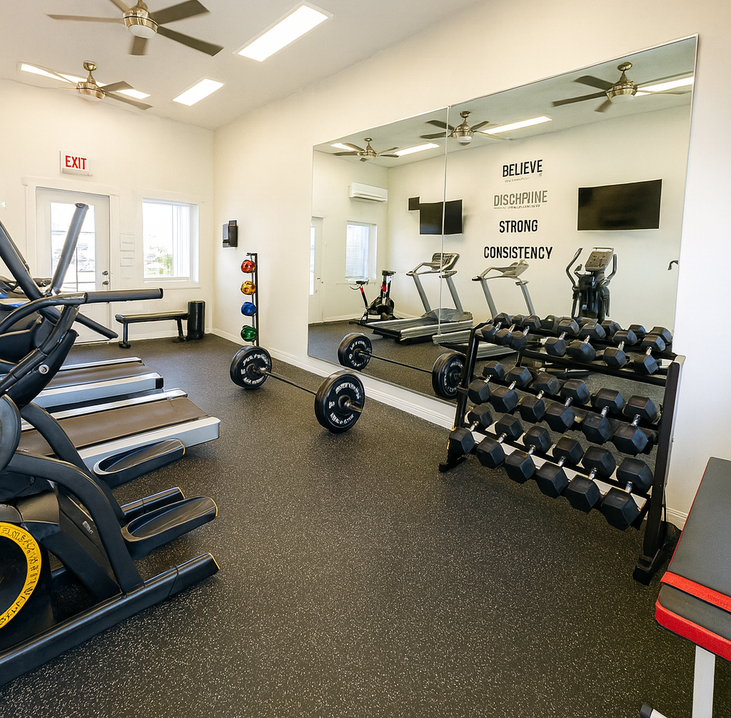 Gym interior with treadmills, weights, and exercise equipment against a large mirror.