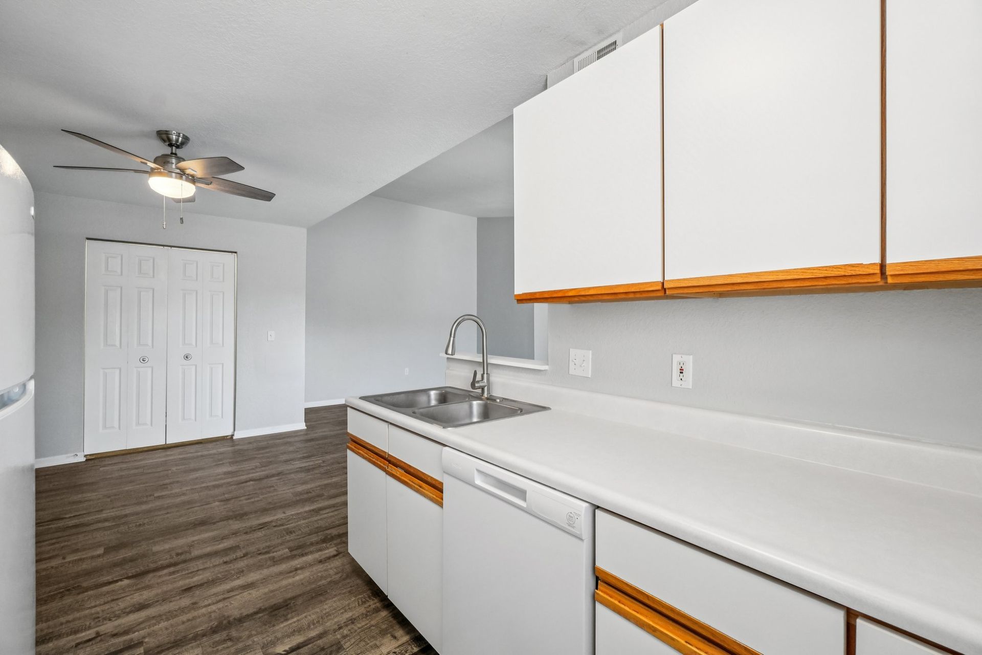 Kitchen with white cabinets, silver sink, and wood-look flooring.
