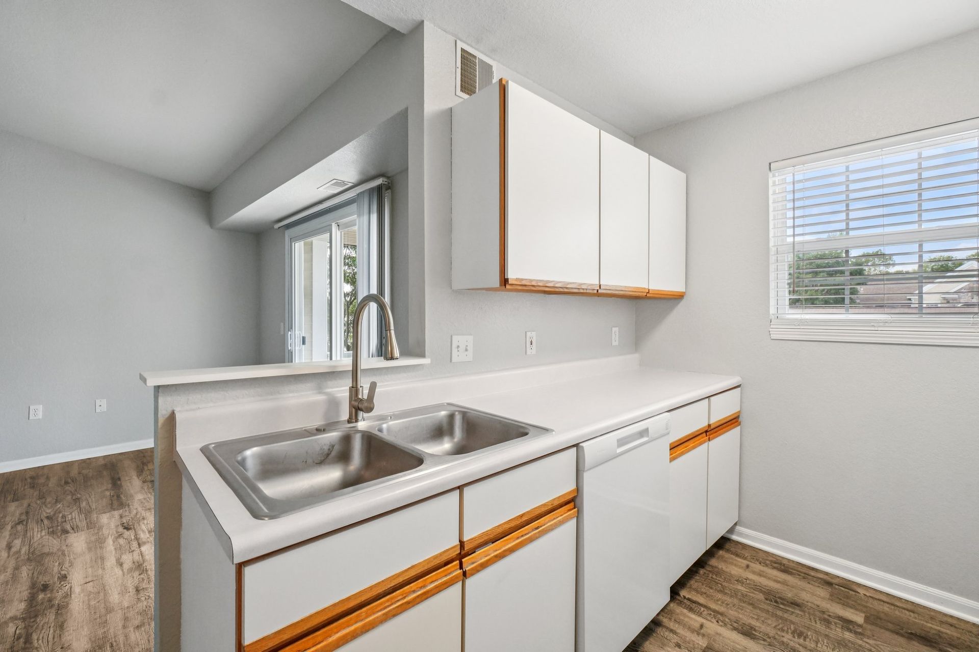 Kitchen with white cabinets, double sink, and a window.