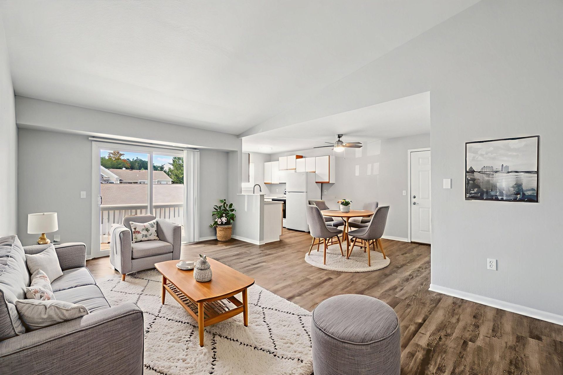 Living room with gray furniture, wood floors, and open kitchen.