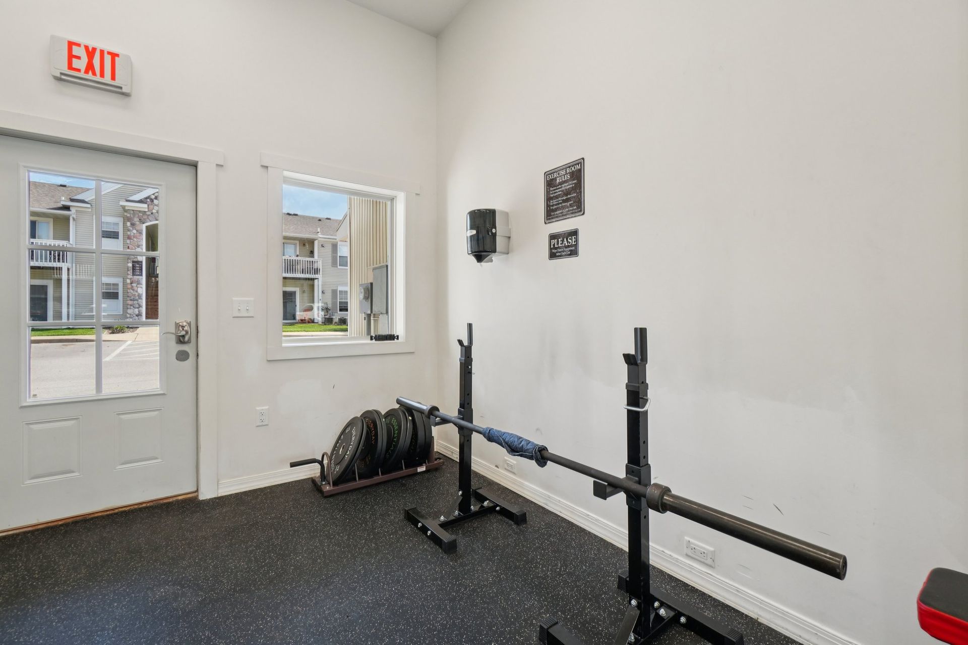 Weight room with squat rack, weights, and exit door.