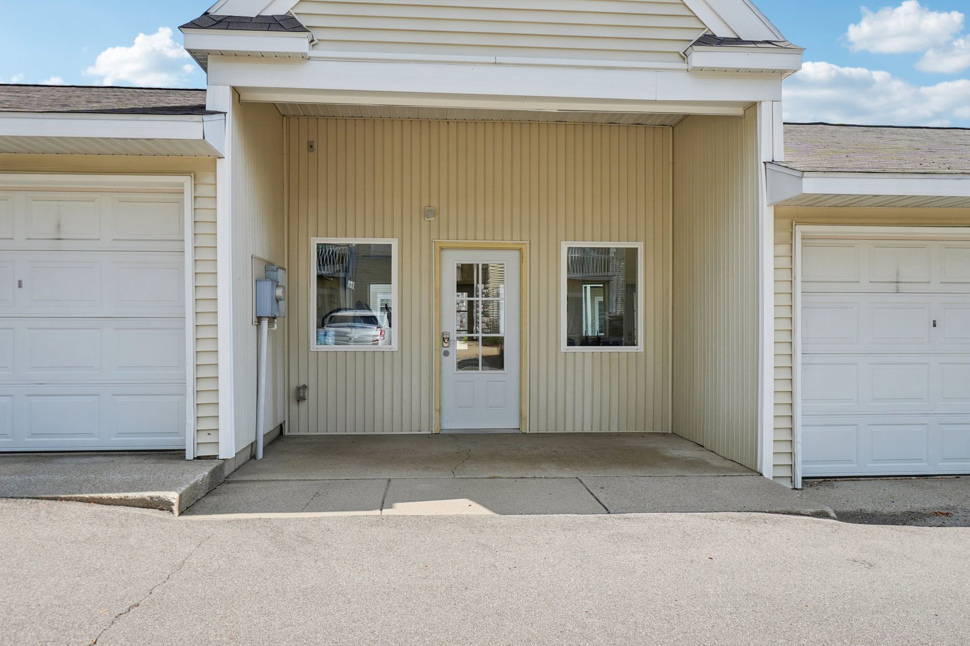 Building with white garage doors and a central entrance with a door and windows.