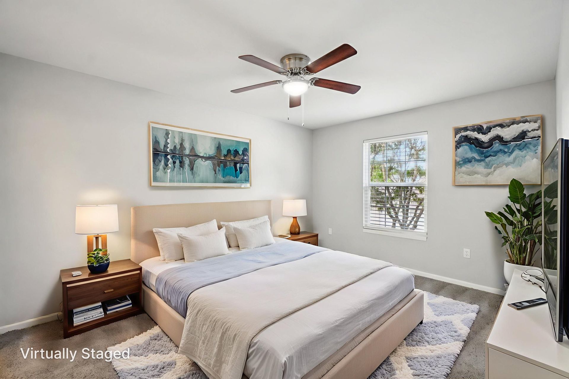 Bedroom with bed, nightstands, artwork, and ceiling fan. Light blue and neutral tones dominate.