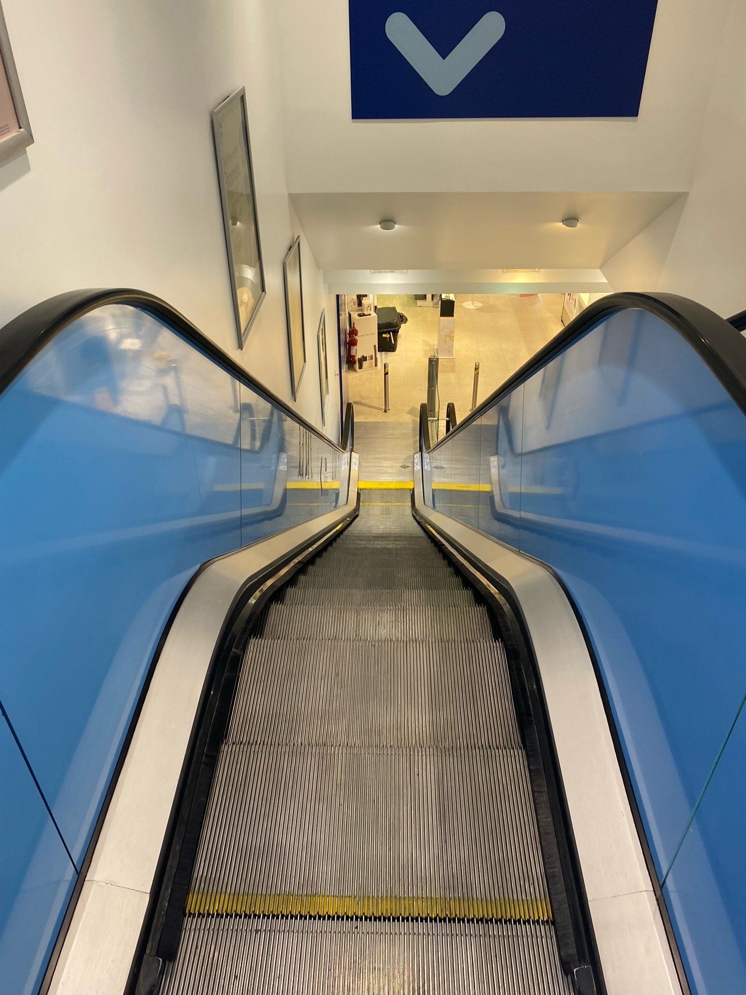 A blue and white escalator with a blue arrow pointing up