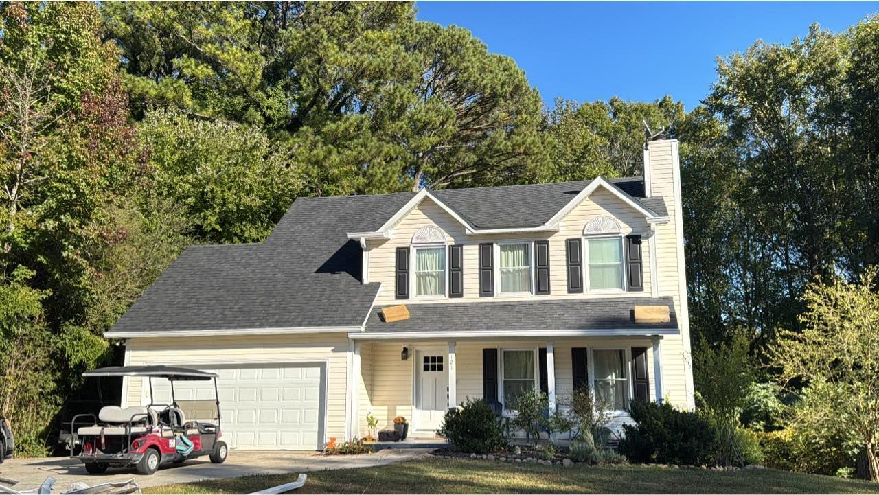Two-story beige house with black shutters, dark gray roof, and a golf cart parked in front.
