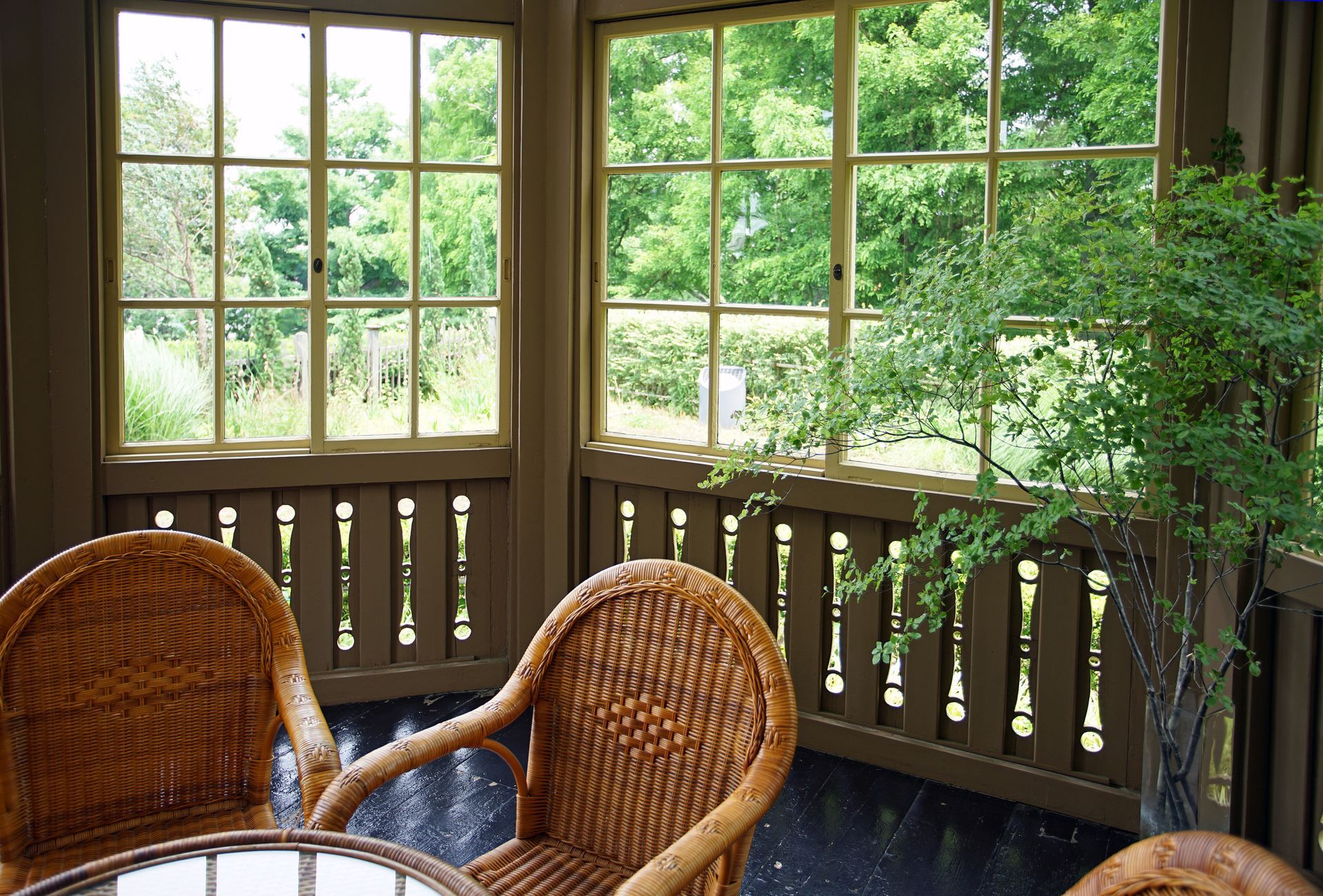 Two wicker chairs and a table in front of a window