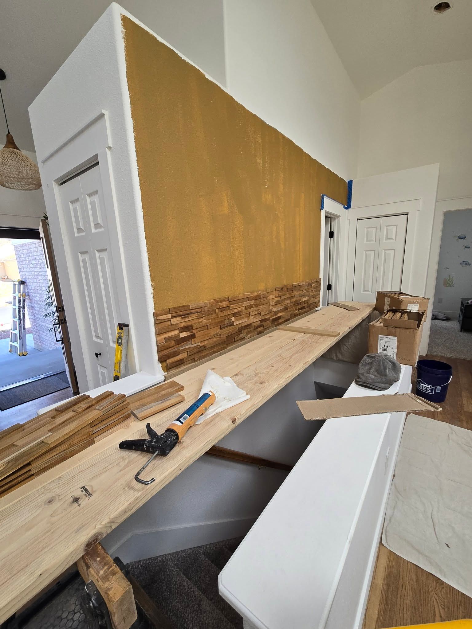 Interior renovation with wood trim installed, tools on a long workbench, and a doorway in the background
