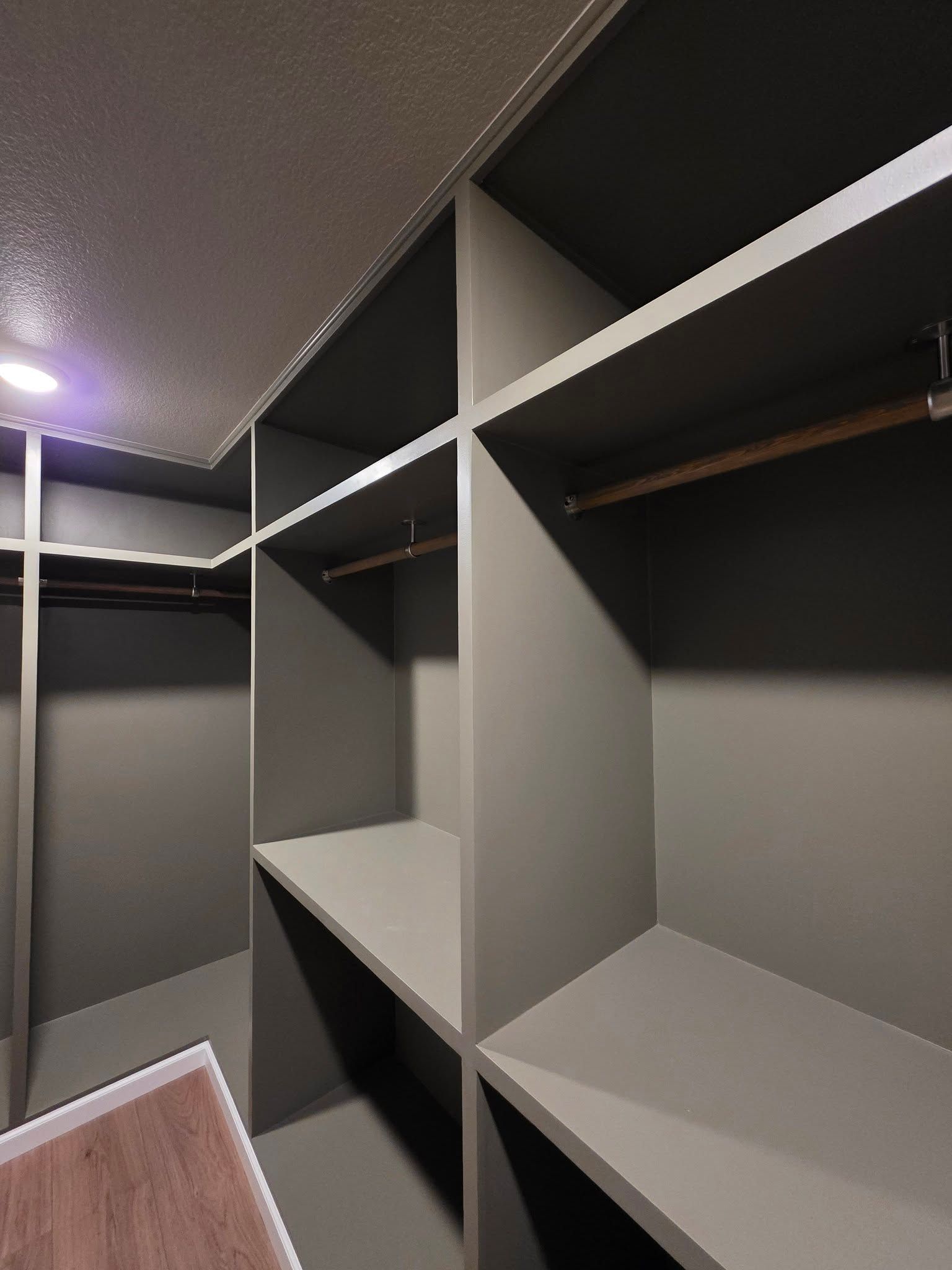 Empty walk-in closet with gray shelves and hanging rods, viewed from the doorway.