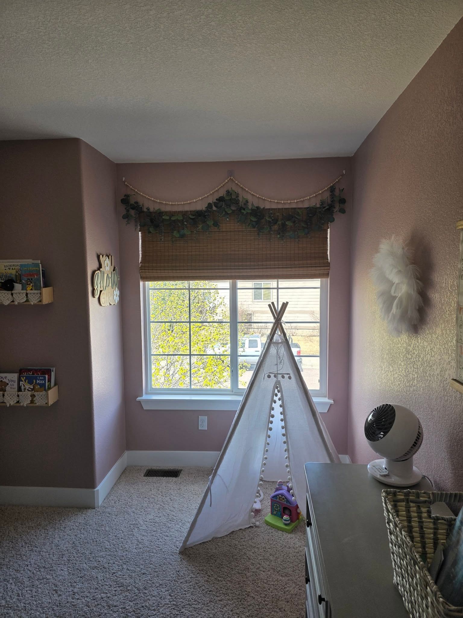 Cozy bedroom with a window, teepee tent, carpet, and decorative wall shelves.