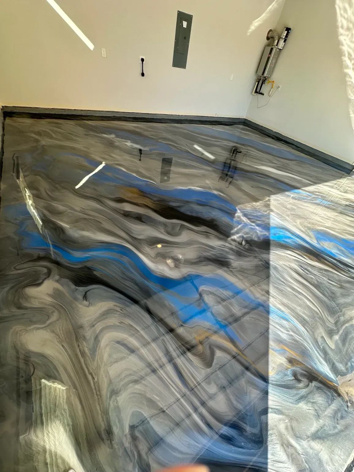 Epoxy flooring with blue and gray swirls in a room with white walls.