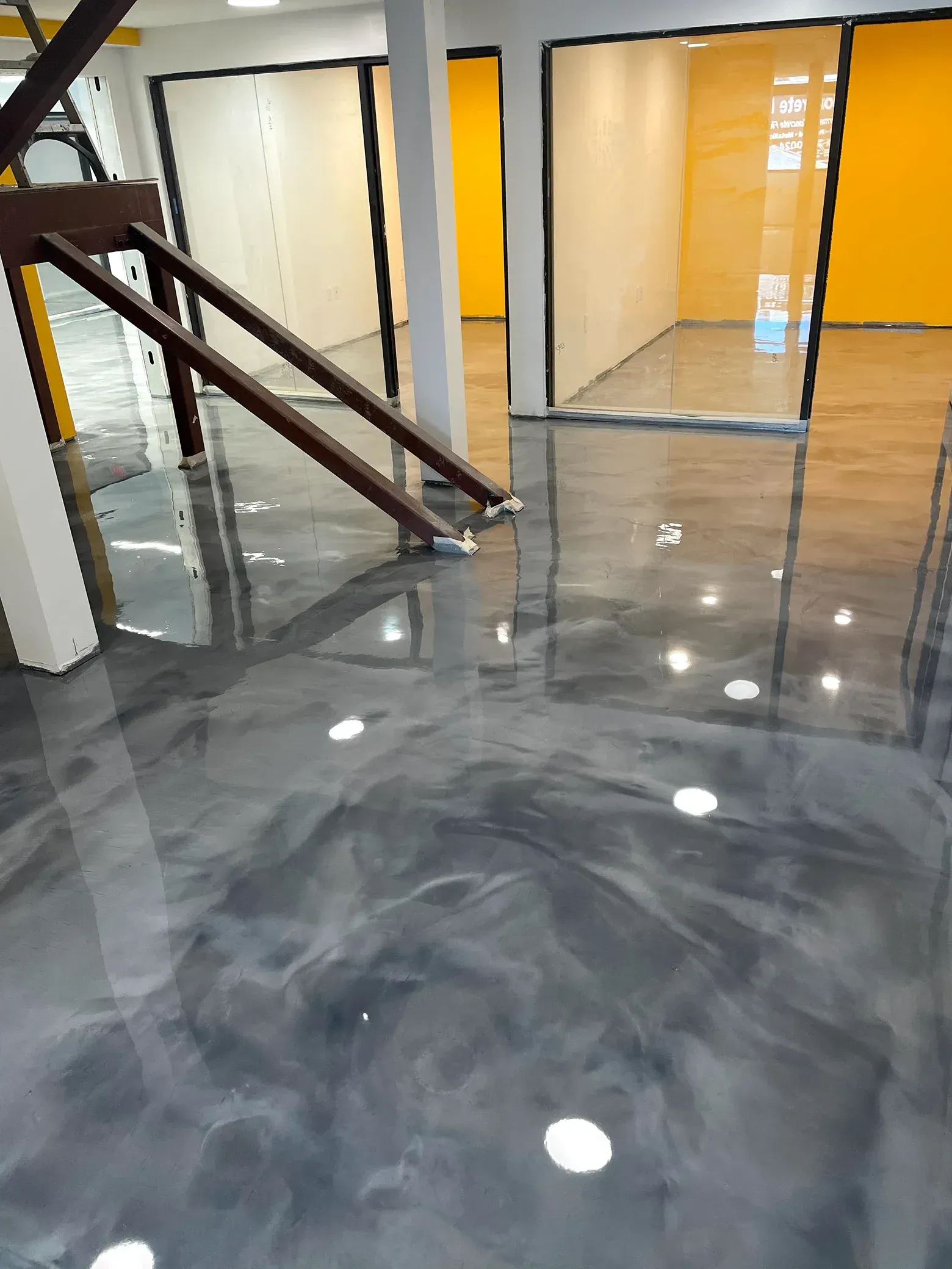 Gray epoxy floor reflecting light in a room with yellow and white walls.