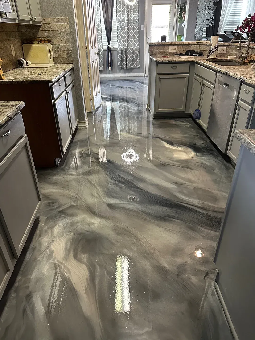 Metallic epoxy floor in a kitchen with gray cabinets and countertops.