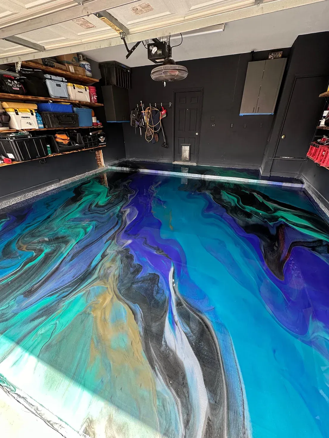 Garage with an epoxy floor featuring swirling blue, teal, purple, black, and gold patterns.