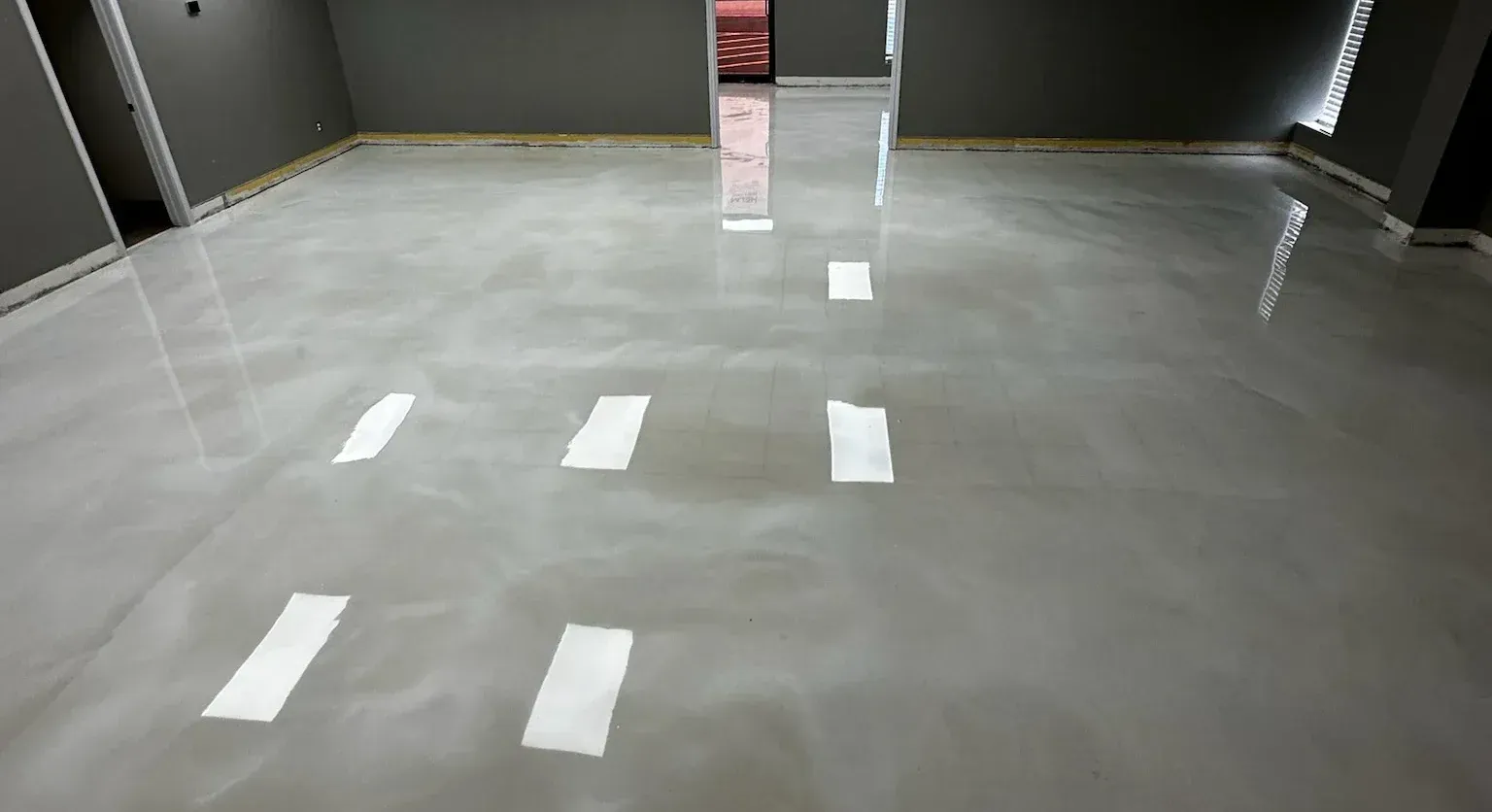 Shiny, light gray epoxy floor with reflections in a room with gray walls.