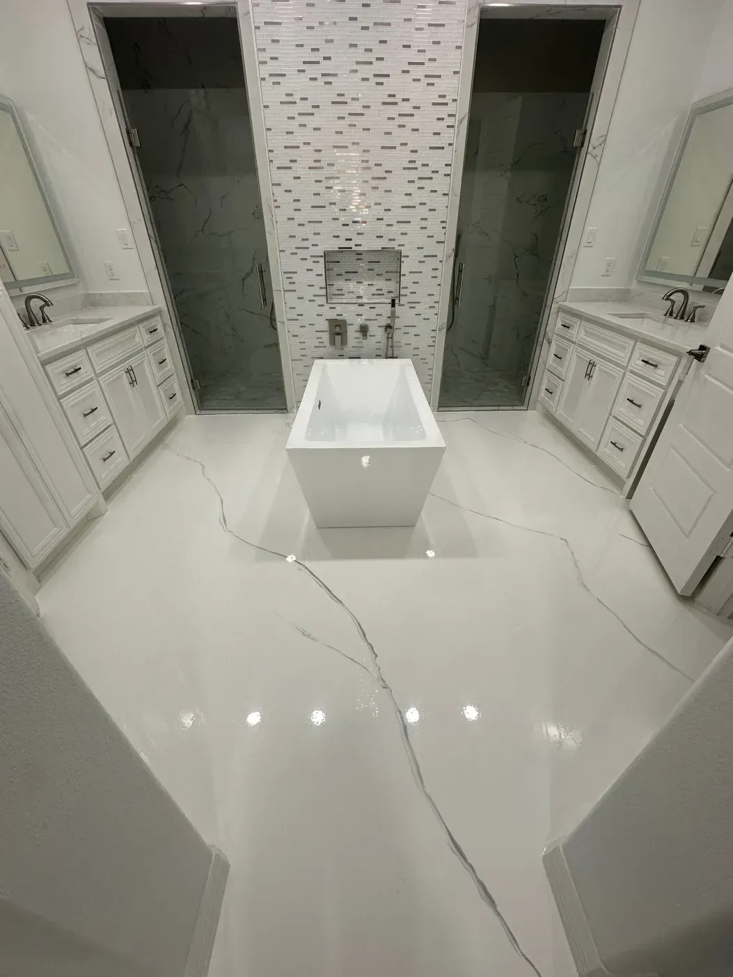 Modern white bathroom with freestanding tub, two showers, and double sinks. White and gray accents.